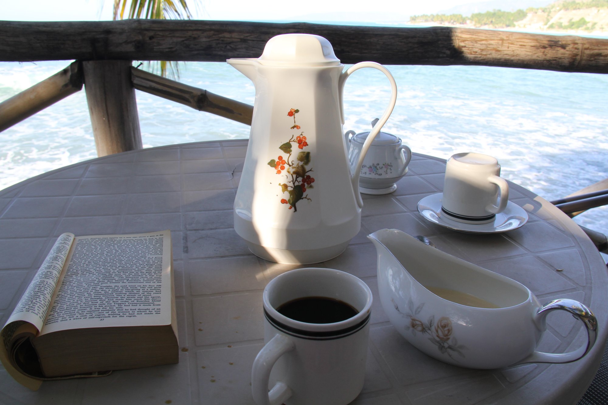 Coffee and an open book on a table overlooking the sea